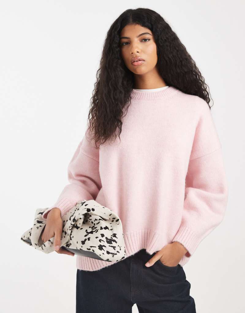 Trend açık pembe renkte, kavisli etek uçlu, oversize yuvarlak yakalı kazak.